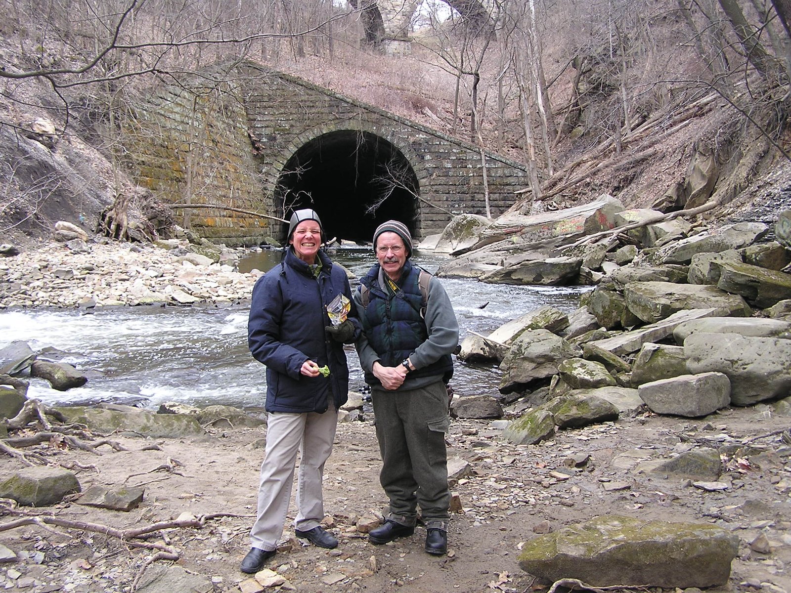 Two club members standing beside Tinker’s Creek in front of a stone tunnel